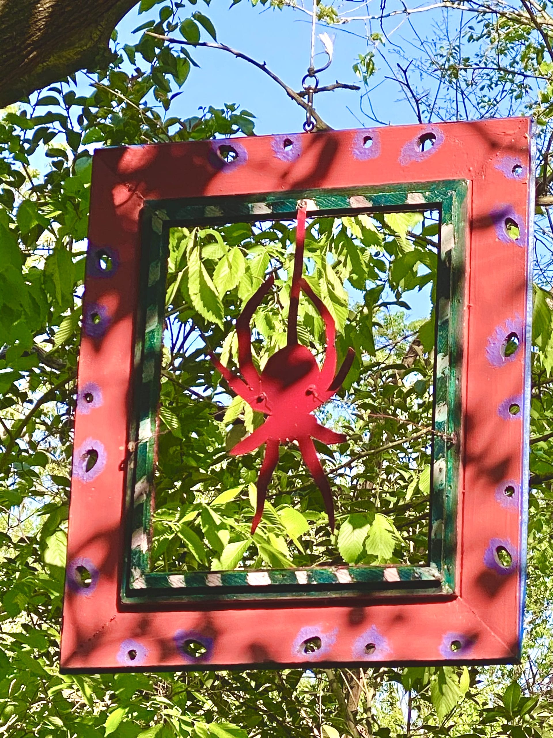 Wooden cut our spider inside frame hanging from tree branch
