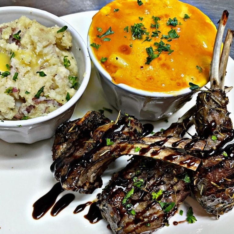 A plate of mashed potatoes, macaroni and cheese, and lamb chops
