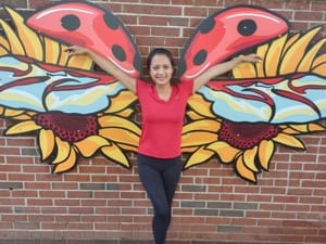 A women poses in front of the Portsmouth Public Art Wings entitled "Lovely Ladybug"