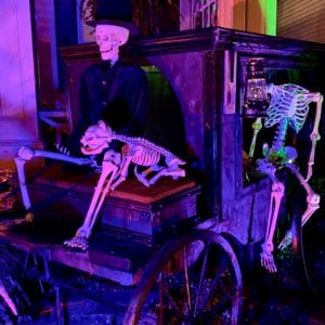 Skeletons posed on a stage coach under a blacklight 
