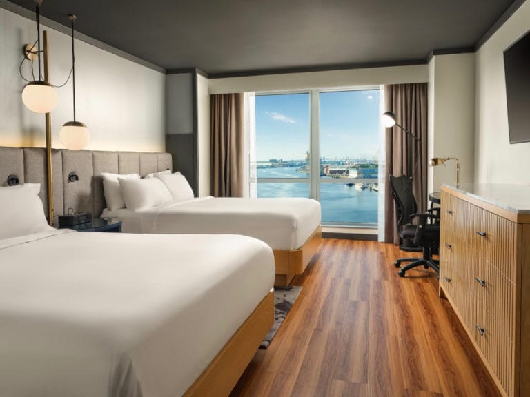 A guest room with two queen beds overlooking the water A guest room with two queen beds overlooking the water