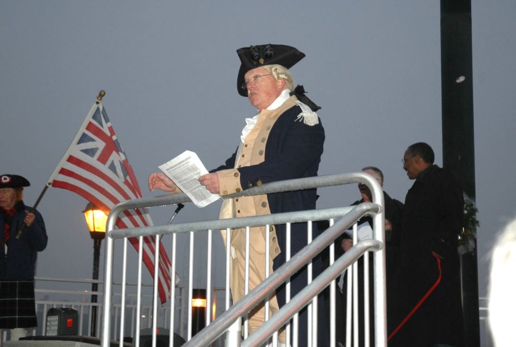 A reenactor holds a script as he addresses a crowd 
