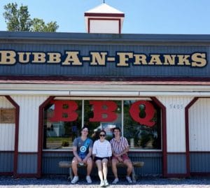 Three patrons sit on a bench outside of Bubba-N-Franks in Portsmouth, Virginia
