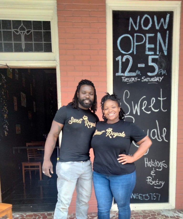 The owners of Sweet Royale Hot Dogs and Poetry pose outside of their Portsmouth, Virginia storefront