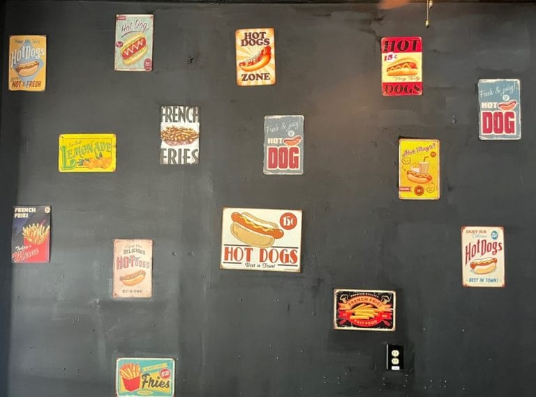 A wall of vintage hotdog signs inside Sweet Royale Hot Dogs and Poetry