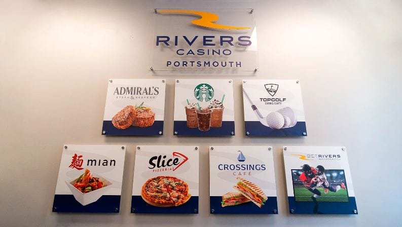 Signs for various restaurants and activities displayed on a wall at Rivers Casino in Portsmouth, Virginia.