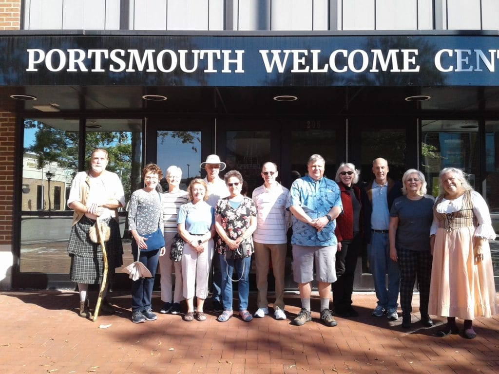 Mary Veale and the Colonials in front of the Portsmouth Welcome Center doors with a group of people.