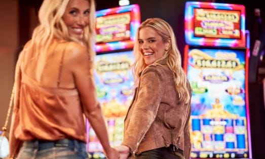 Two women stand by two slot machines inside the Rivers Casino in Portsmouth, Virginia.